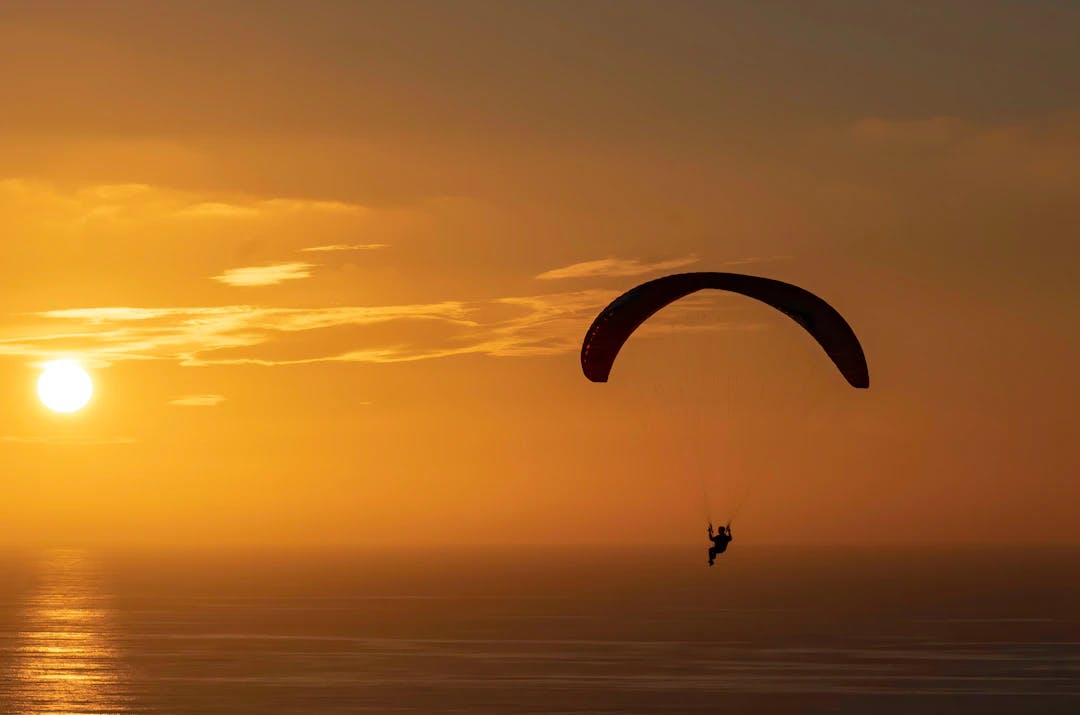 a person is para sailing in the ocean at sunset