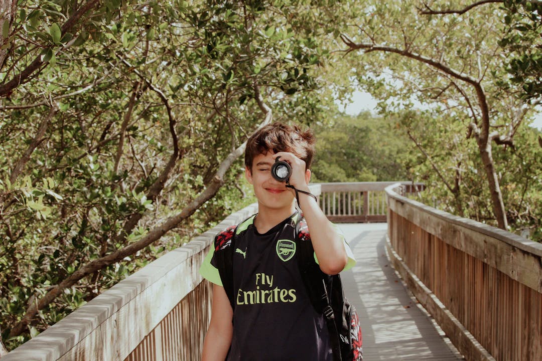 a young boy standing on a bridge looking through a pair of binoculars