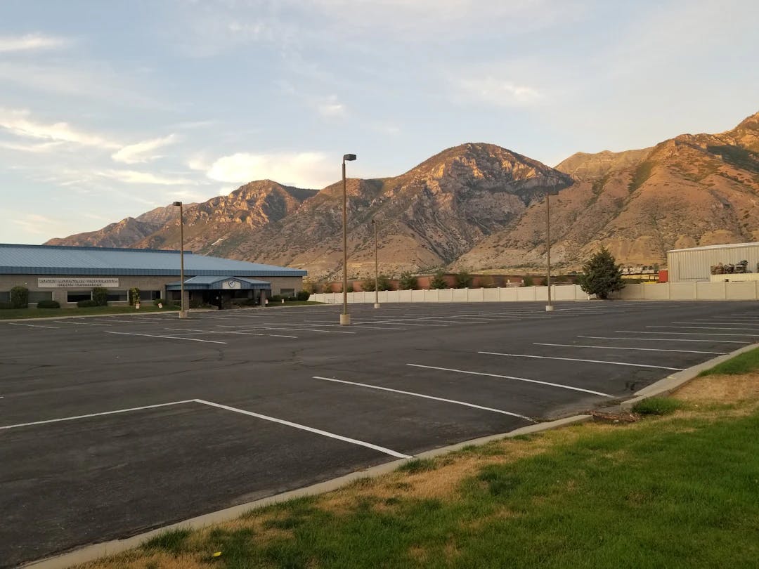 a parking lot with a building and mountains in the background